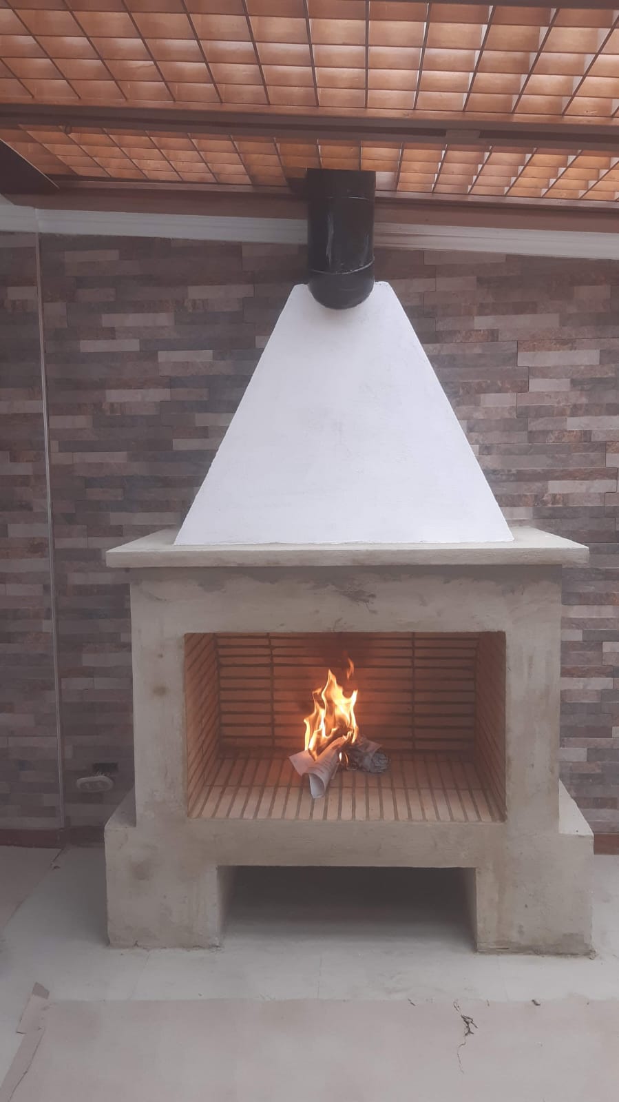 Chimenea de obra en mármol travertino con fuego encendido